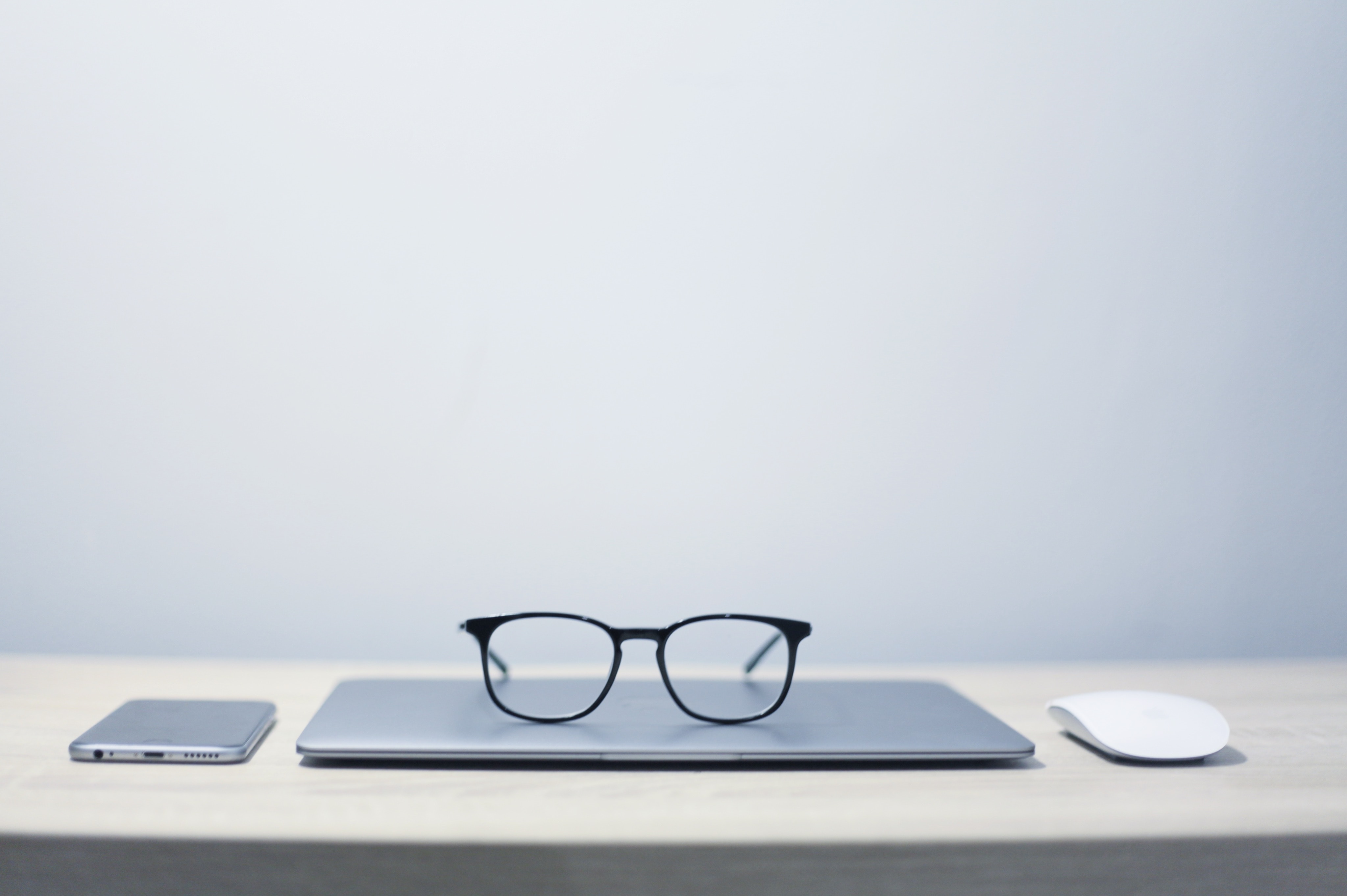 closed laptop on a desk with glasses