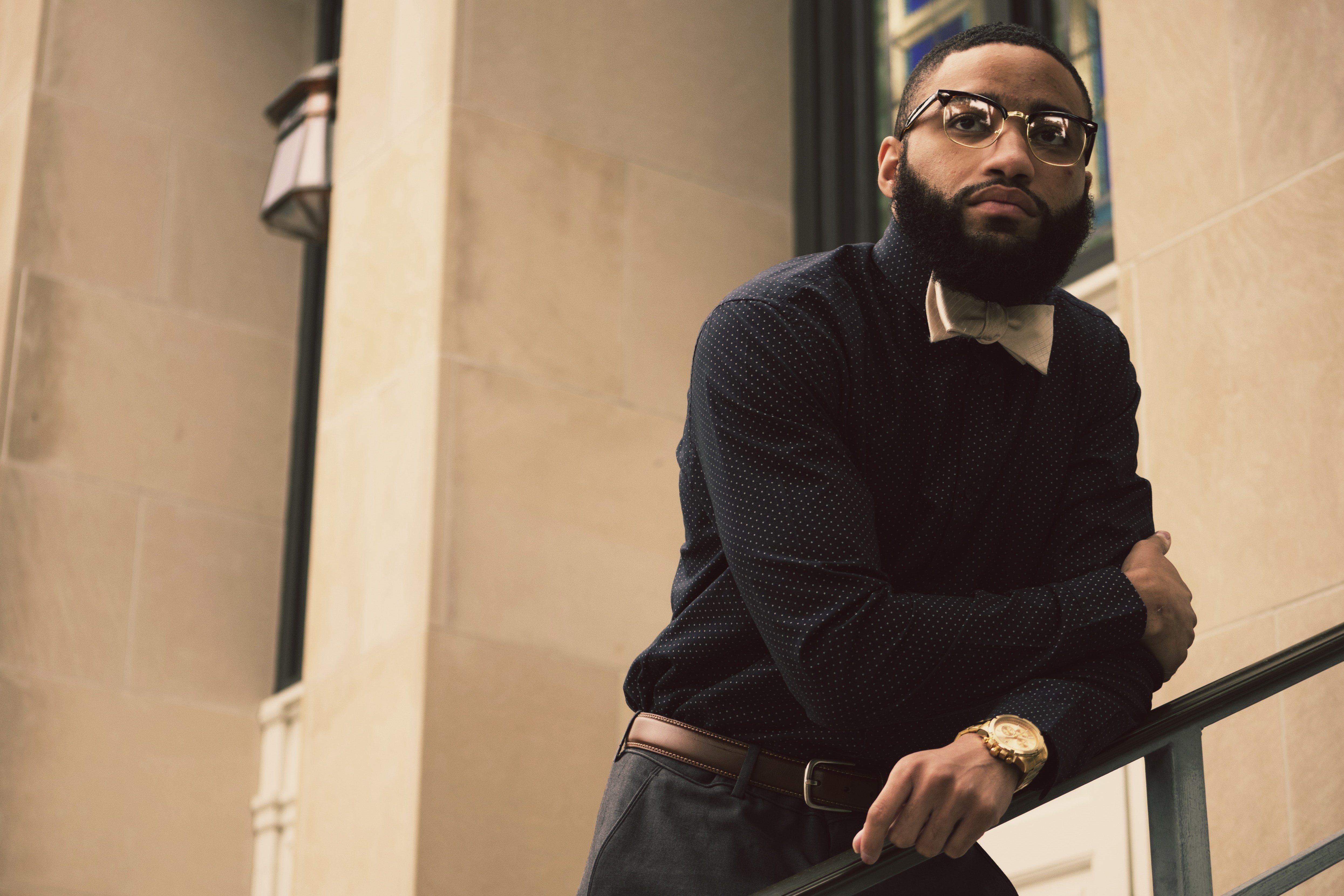 Man with glasses leans on railing