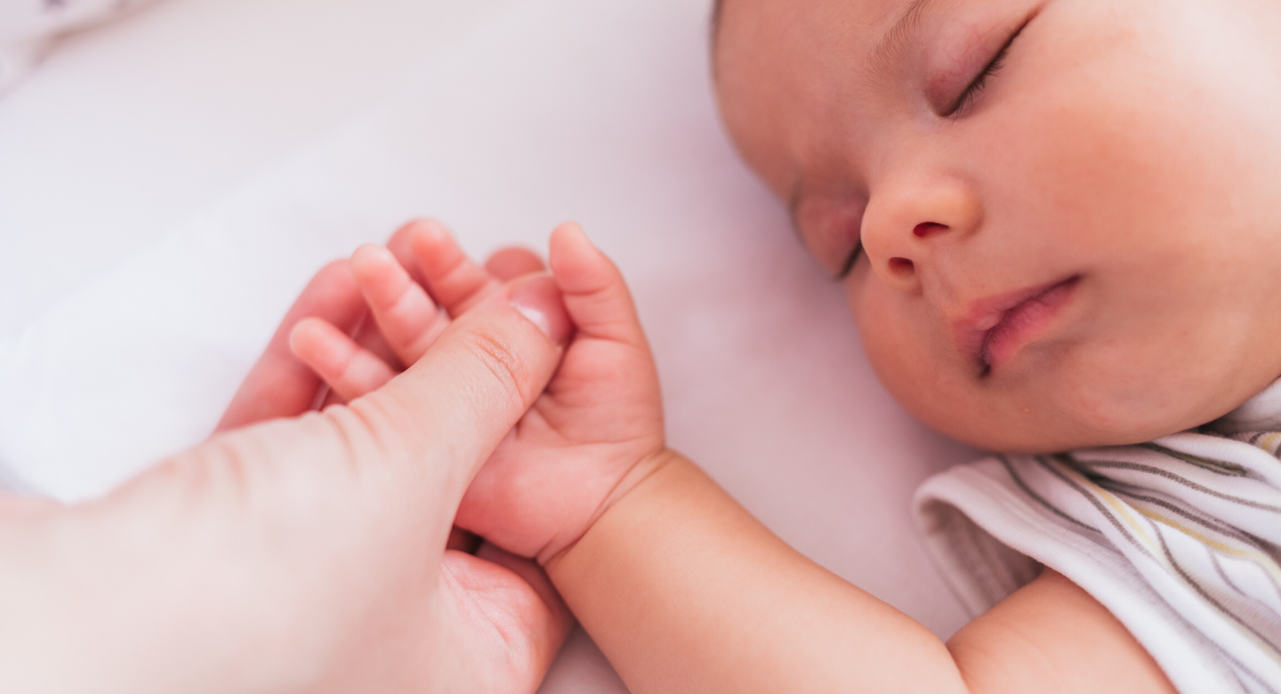 Sleeping baby with adult hand