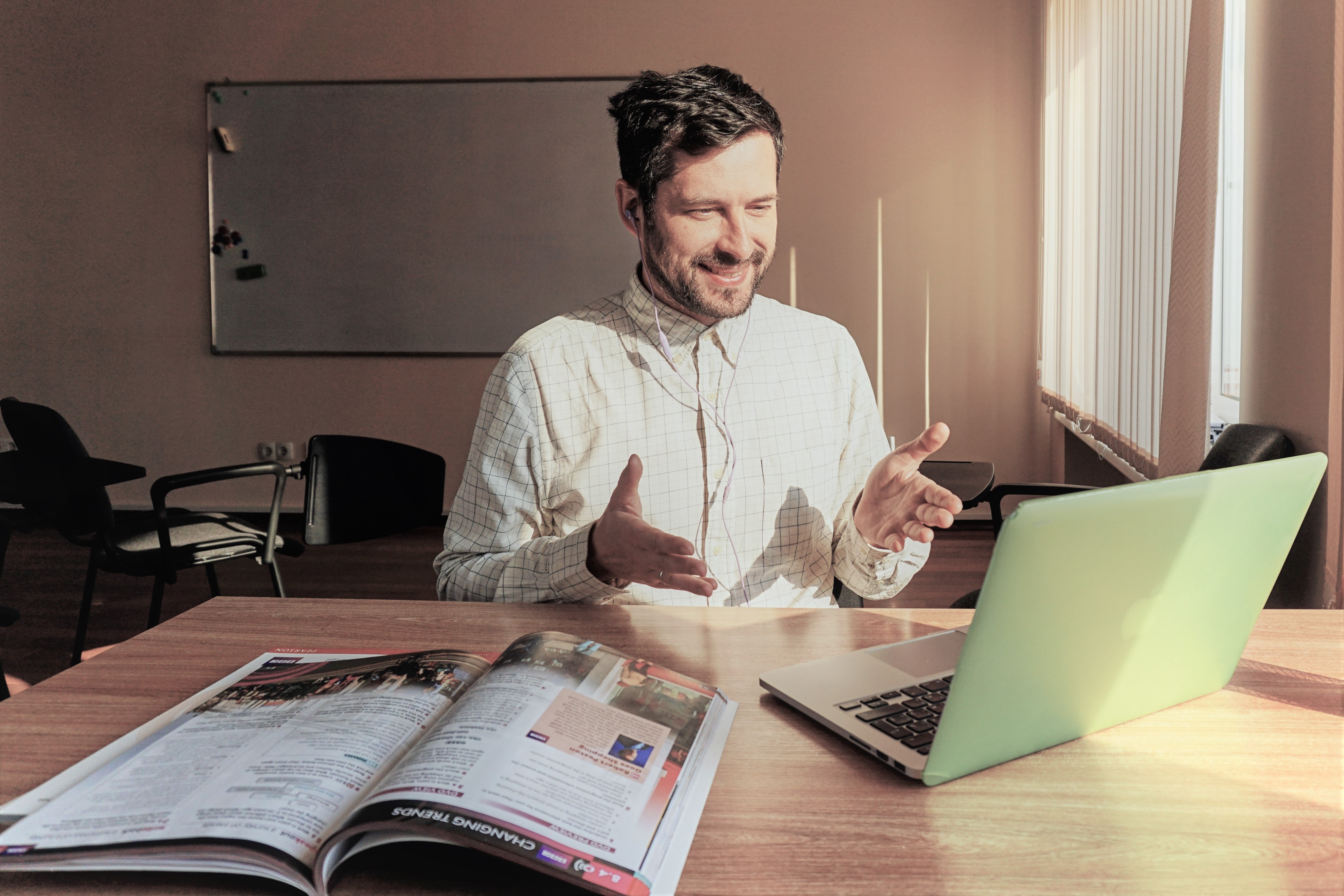 Man on a video conference call with laptop and open magazine