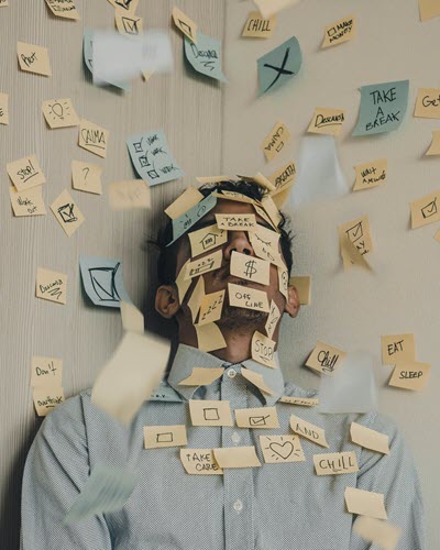 Business person covered in post it notes