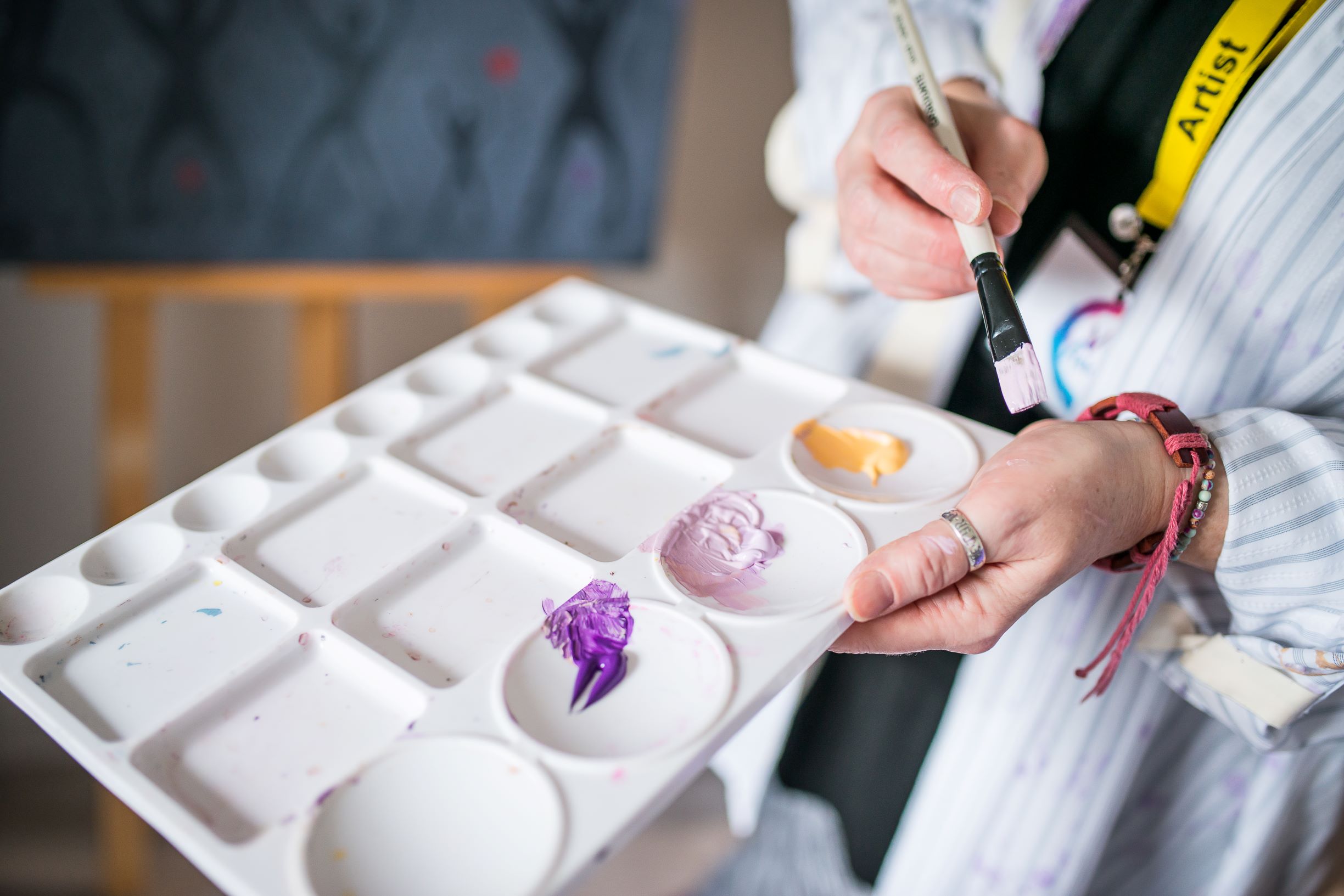 picture of a pair of hands holding a paintbrush & palette