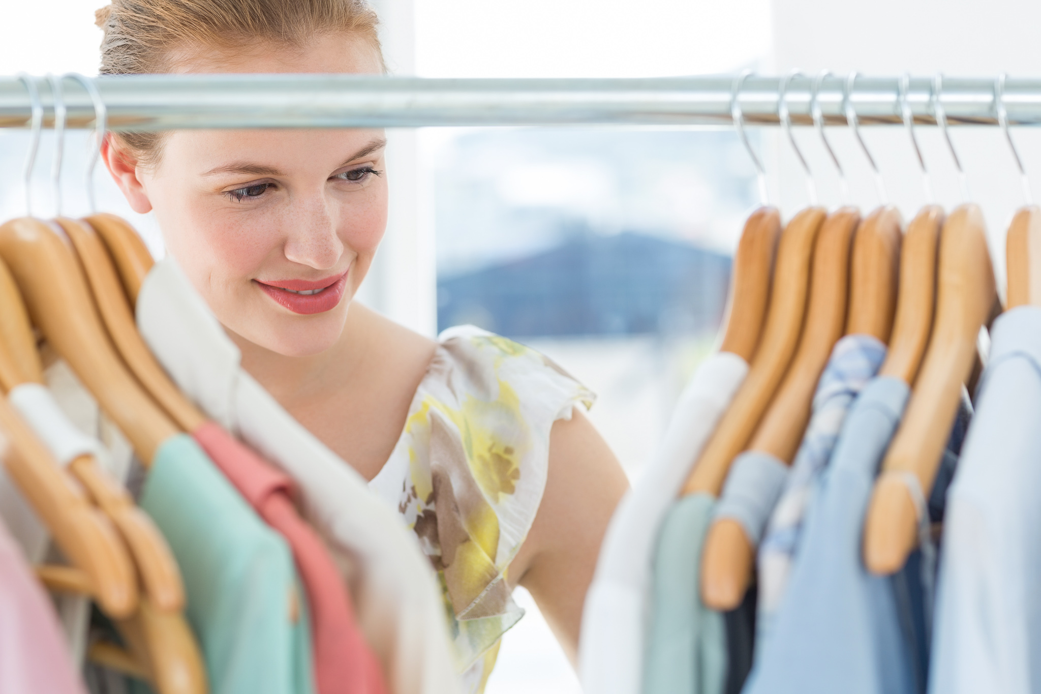 Smiling woman looking through clothes hanging in her closet.