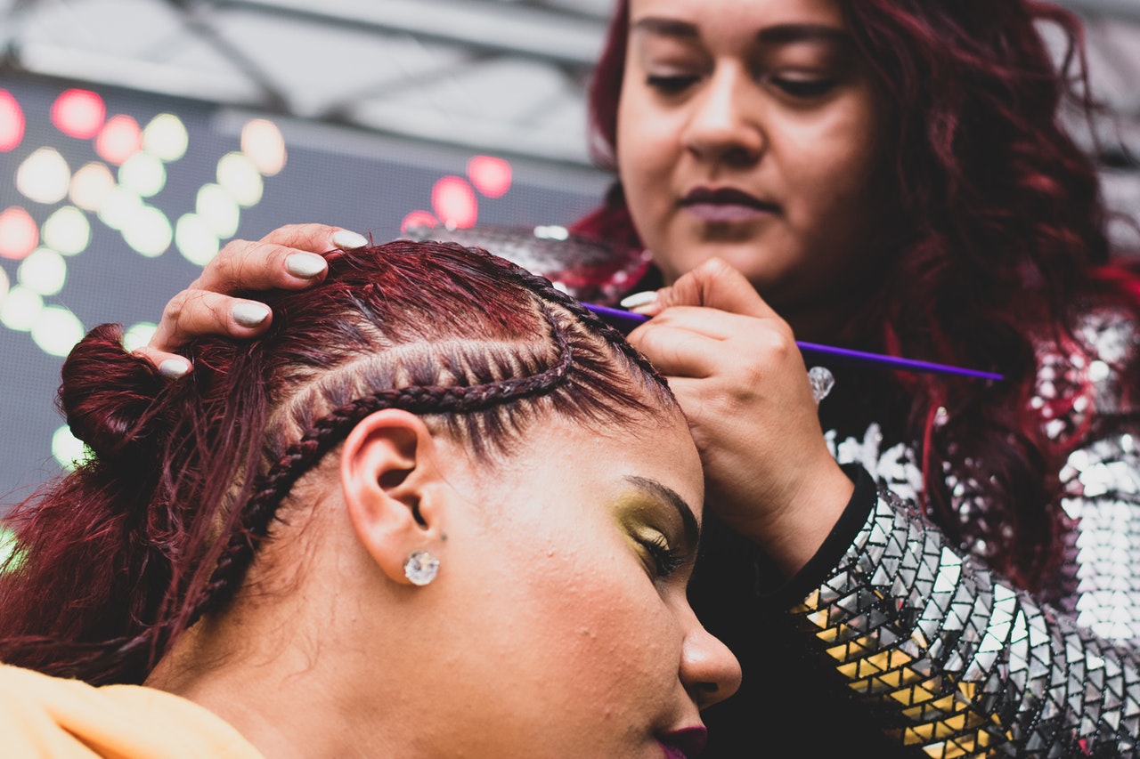 Woman Cornrowing a young ladies hair.