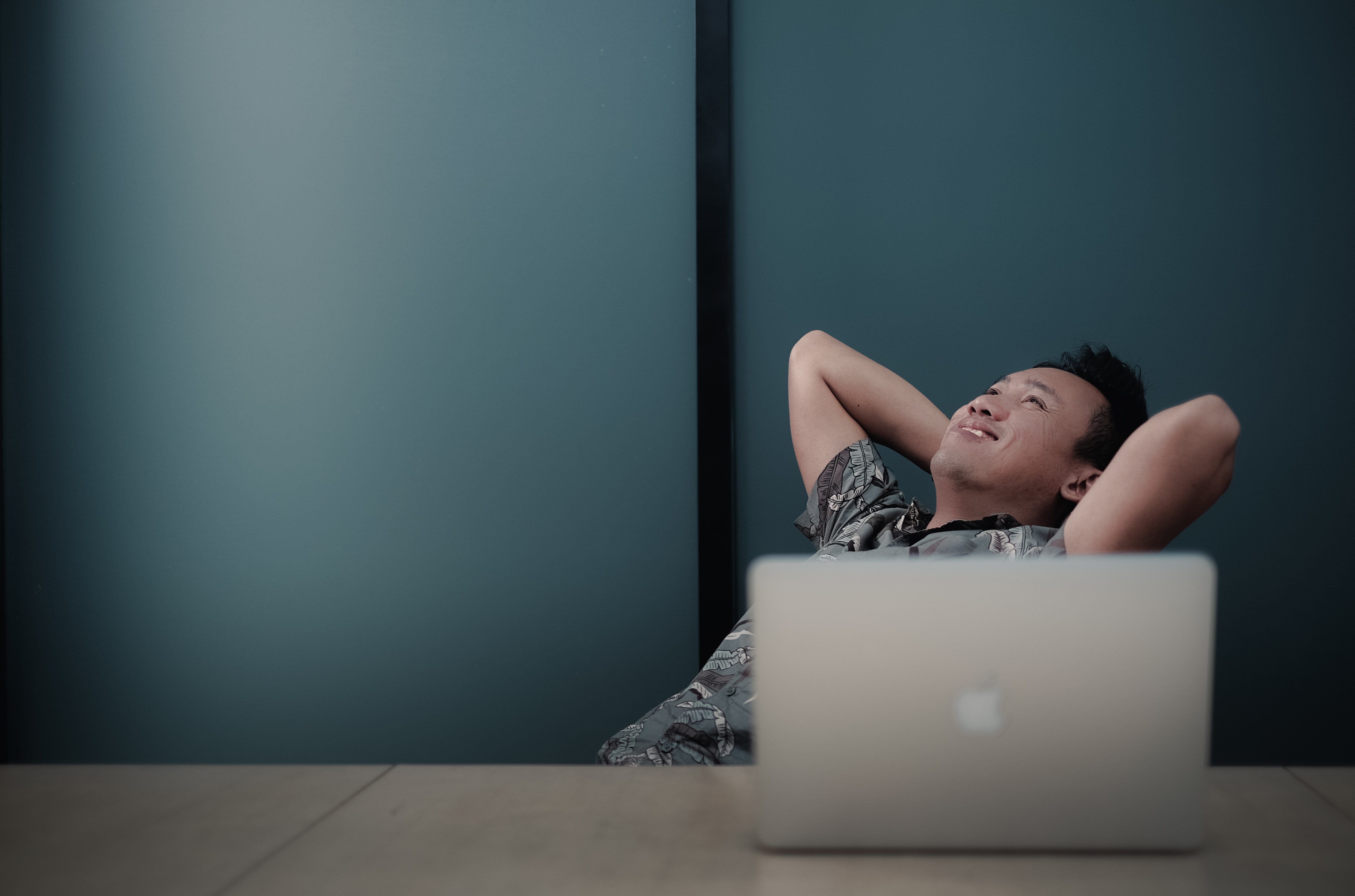 Asian man feeling happy and relaxing by his mac computer