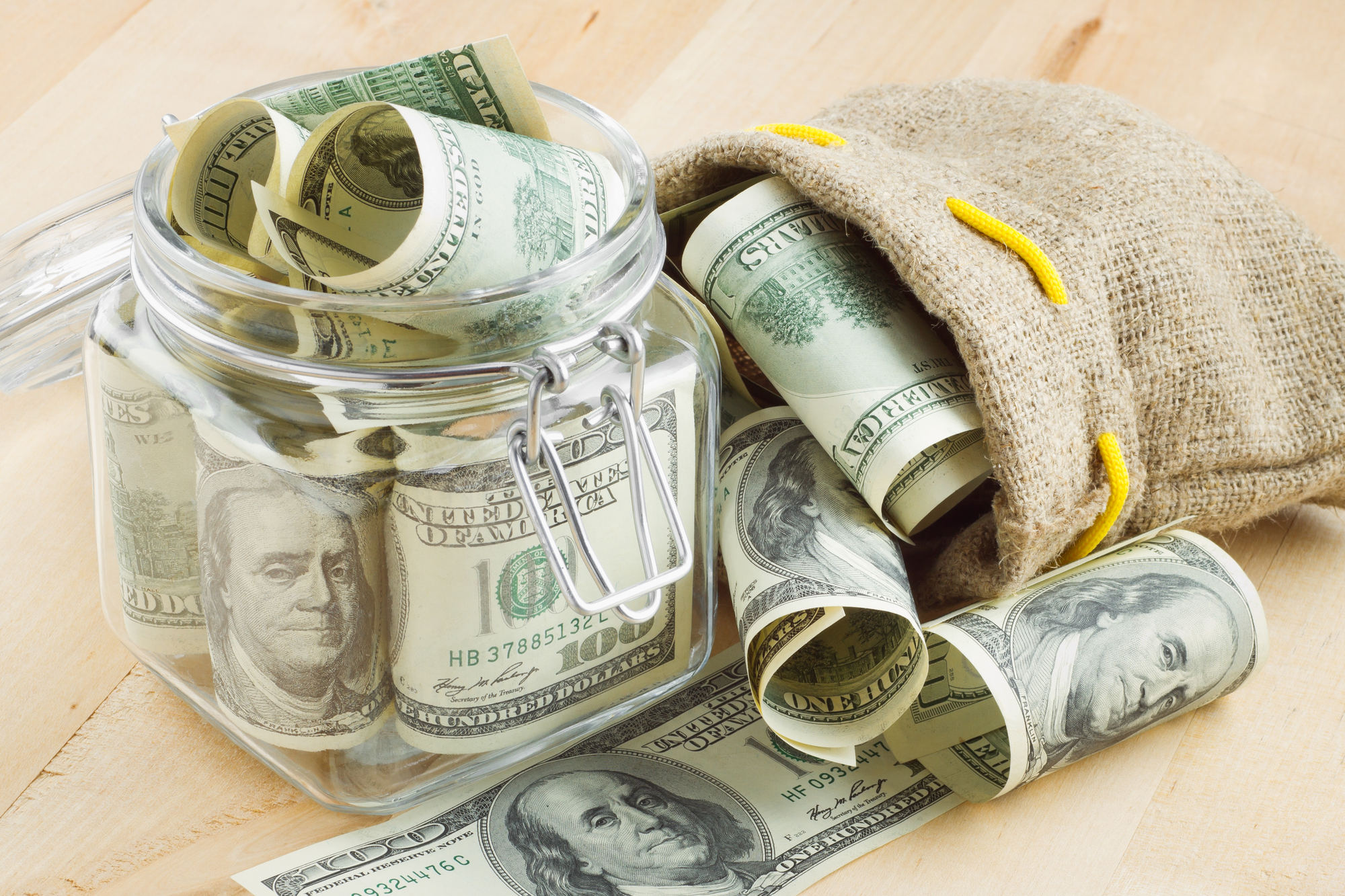 female hands counting dollar bills from open purse with notebook and calculator in background