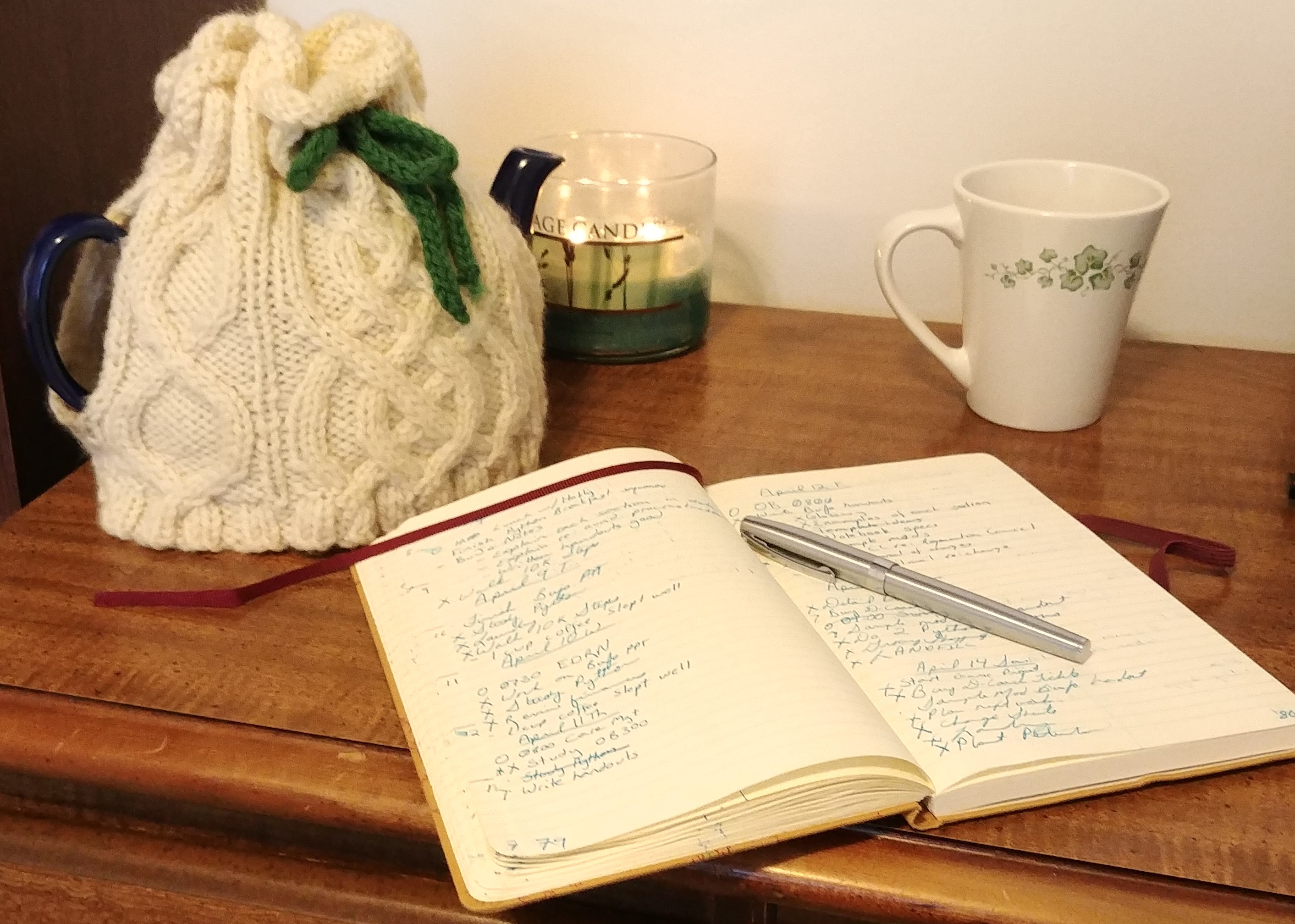 A notebook, candle and teapot with cozy